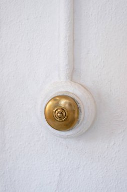 Klasik yuvarlak şekil ve beyaz duvarda altın renkli ışık düğmesi