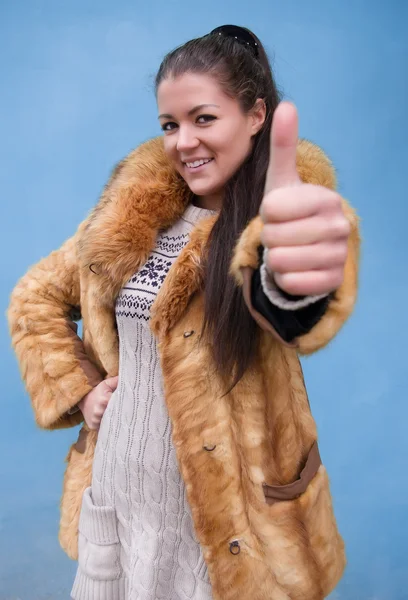 Mulher bonita em um casaco de pele mostrando polegar para cima — Fotografia de Stock