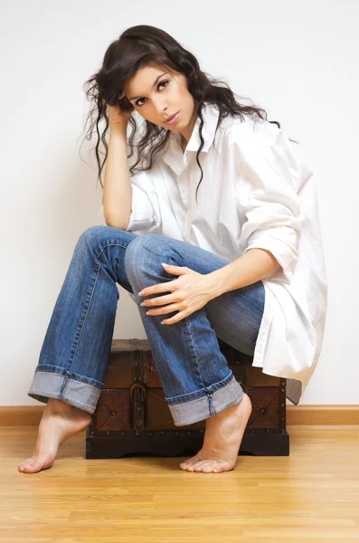 Beautiful brunette sitting on the coffer. — Stock Photo, Image