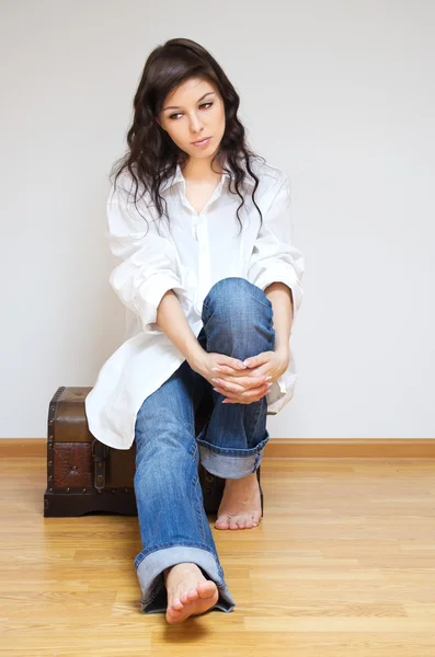 Beautiful brunette sitting on the coffer. — Stock Photo, Image