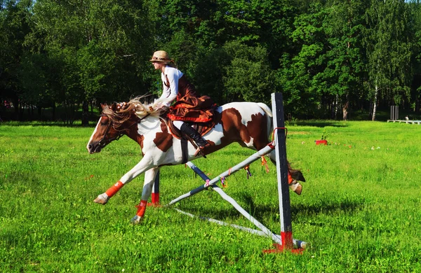 Ragazza-fantino su un cavallo salta oltre una barriera — Foto Stock