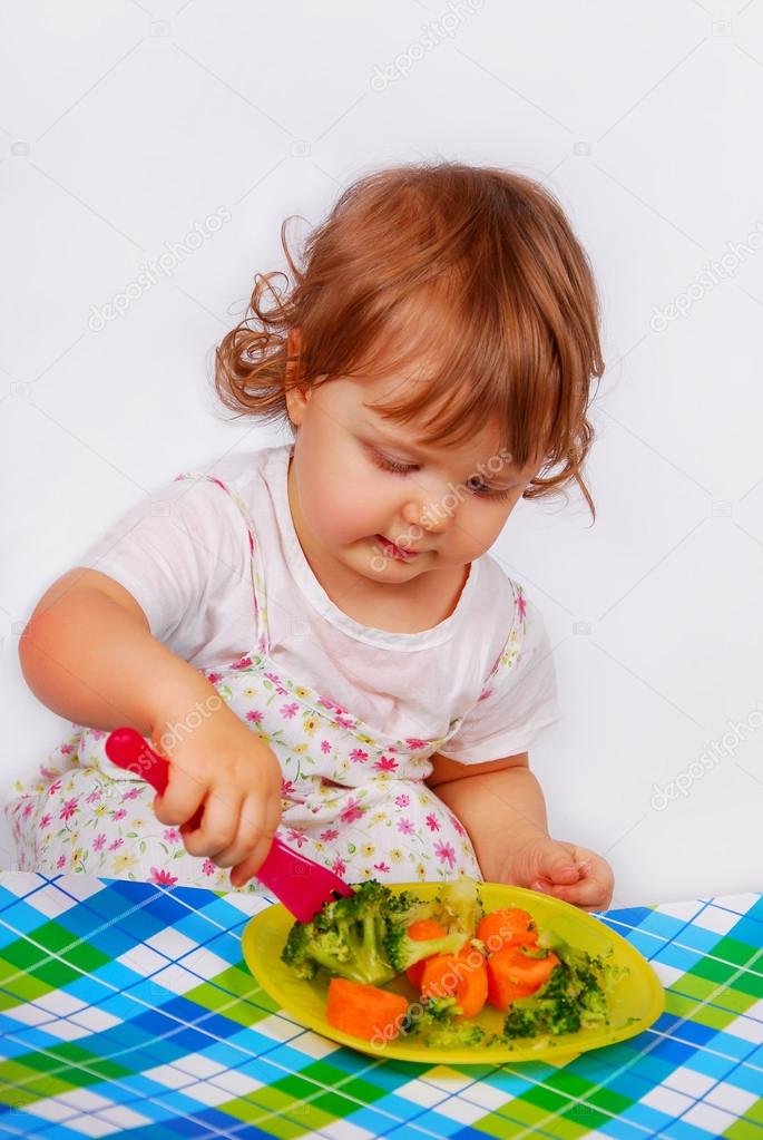little baby girl eating broccoli and carrot