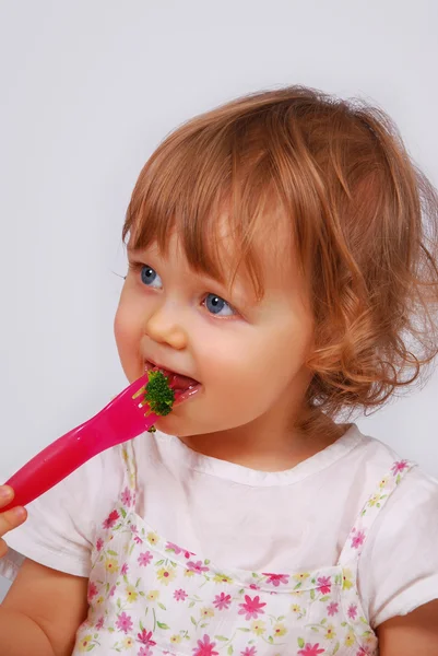 Little baby girl eating broccoli with fork — Stock Photo, Image