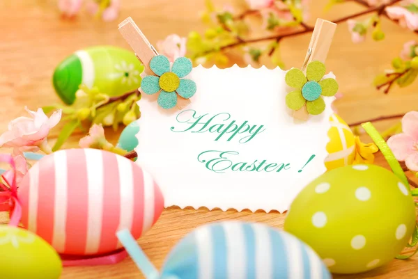 Easter eggs and greetings card on wooden background — Stock Photo, Image