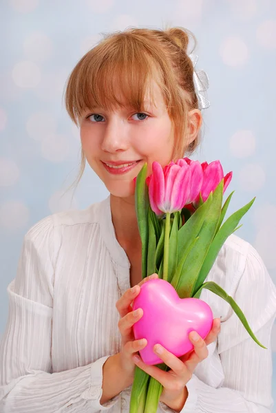 Krásná mladá dívka s růžové tulipány a srdce — Stock fotografie