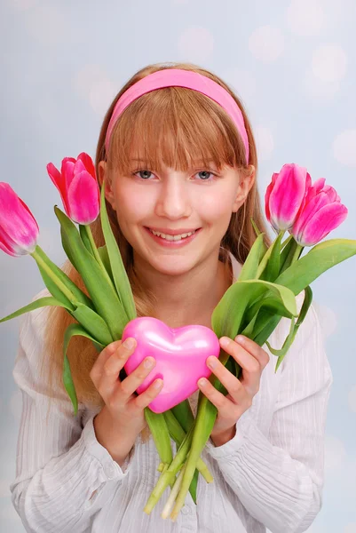 Beautiful young girl with pink tulips and heart — Stock Photo, Image