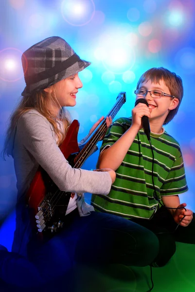 Menina tocando guitarra e menino cantando Imagens De Bancos De Imagens