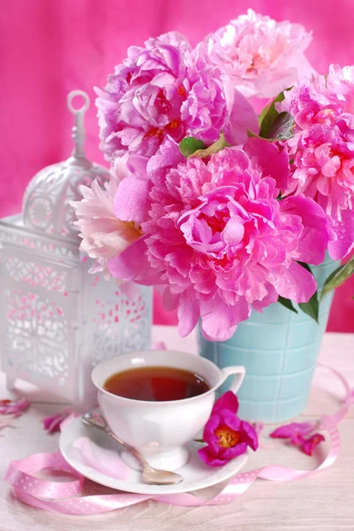 Tasse Tee und Pfingstrosenblüten — Stockfoto