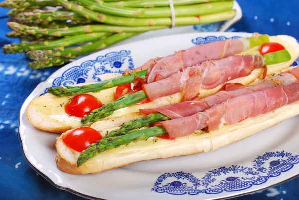 Baguette with green asparagus wrapped in ham — Stock Photo, Image