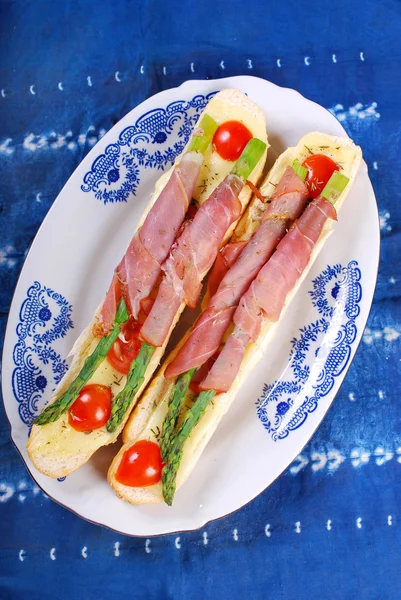 Baguette with green asparagus wrapped in ham — Stock Photo, Image