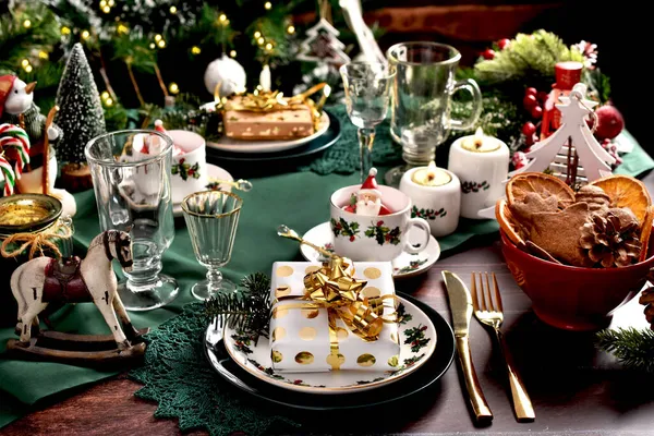 プレート上のギフトボックス 美しい装飾品や緑のテーブルクロスとクリスマステーブルの設定 — ストック写真