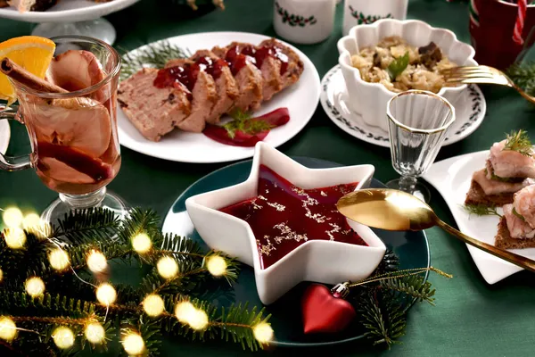 緑のテーブルクロスと装飾とお祝いのテーブルの上に星形のボウルに赤ボルシチと伝統的なクリスマスイブ料理 — ストック写真