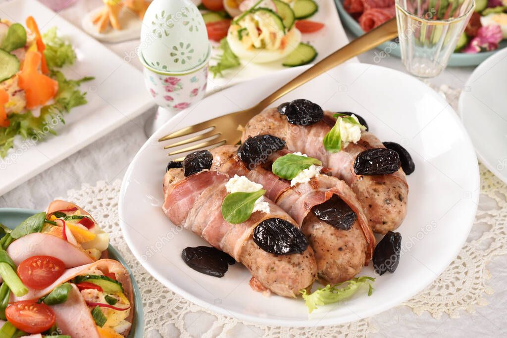Easter table with grilled white sausage wrapped in bacon with prune and horseradish