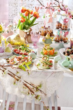 Geleneksel yemekler, çiçekler ve pastel renklerle süslenmiş Paskalya sofrası ile klasik tarz iç dekorasyon