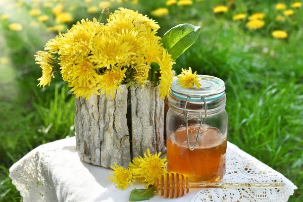 新鮮なタンポポの花と草原で蜂蜜の瓶を持つ小さなテーブル — ストック写真