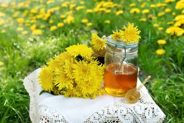草地上有一个小桌子 上面有新鲜的蒲公英花和一罐蜂蜜 — 图库照片