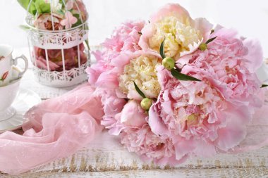 Beyaz ahşap masada yatan pembe ve sarı şakayıklar. 