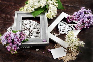 İki çerçeveli koyu ahşap zemin, dantel peçeteler ve taze mor ve beyaz leylak çiçekleri.