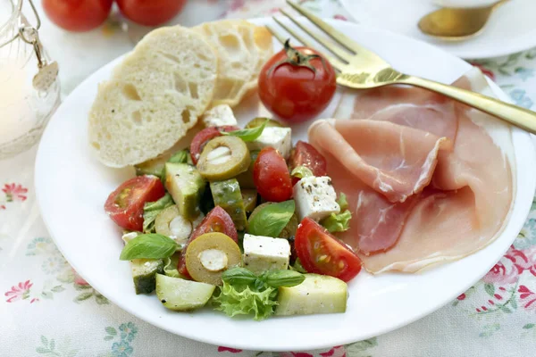 Fresh Mediterraneanstyle Salad Feta Cheese Vegetables Prosciutto Ham White Plate — стоковое фото
