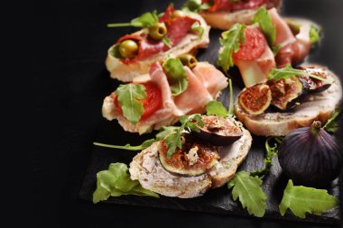 Taze incirli lezzetli sandviçler, jambonlu jambon ya da siyah tahtada roka salamı ve sol görüşlü metin için fotokopi alanı. 