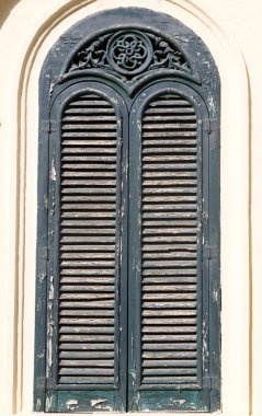 Sarı bir duvar, yeşil ahşap pencere kepenkleri kapalı