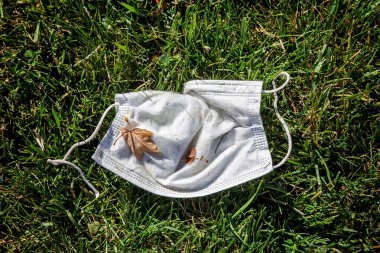 used and dirty disposable face mask on the ground