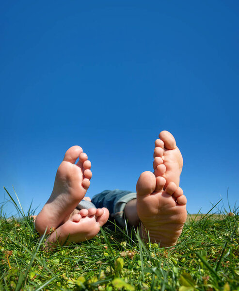 close up of two people feet and their toes laying in grass