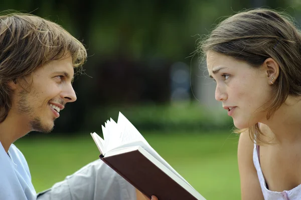 Ένα φίλο και τη φίλη, διαβάζοντας ένα βιβλίο σε ένα πάρκο — Φωτογραφία Αρχείου