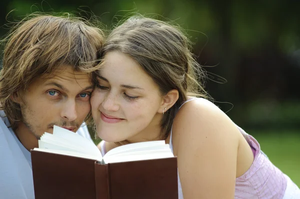 Un petit ami et sa copine lisant un livre dans un parc — Photo