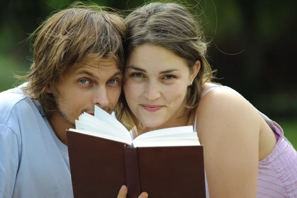 Un novio y una novia leyendo un libro en un parque — Foto de Stock