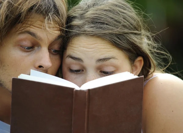 A boyfriend and girlfriend reading a book in a park — Stock Photo, Image
