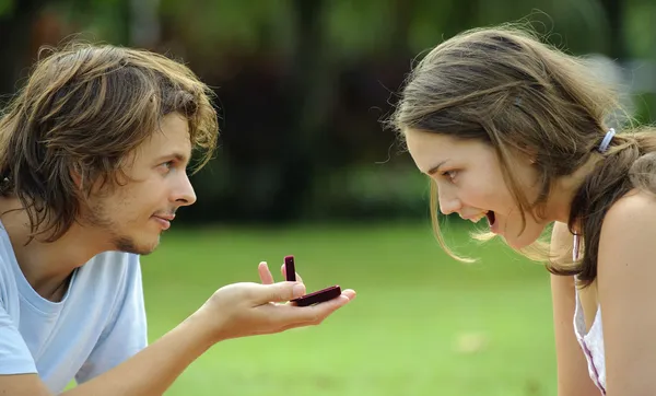 Jongen geeft een meisje een ring in het park — Stockfoto