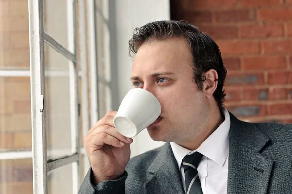 Traje hombre bebe café y piensa —  Fotos de Stock