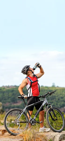 Man drinks on mountain with bicycle — Stock Photo, Image