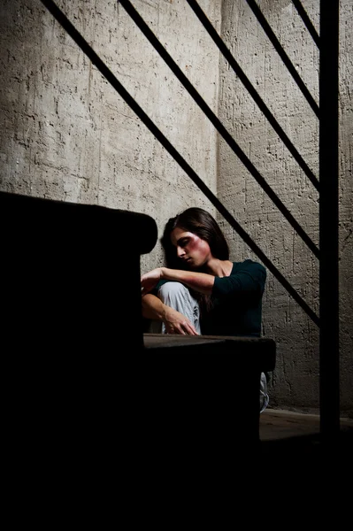 Misshandelte Frau in der Ecke eines Treppenhauses tröstet sich — Stockbild Konzept häuslicher Gewalt angewendet und missbraucht — Stockfoto