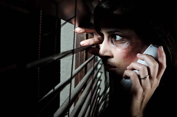 Ängstliche Frau, die durch die Jalousien schaut, um zu sehen, ob ihr Mann zu Hause ist, während sie um Hilfe ruft — Stockbild Hilferuf nach Konzept für häusliche Gewalt — Stockfoto
