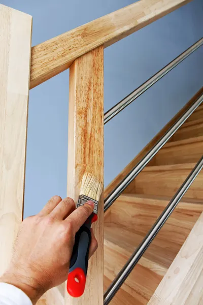 Mão aplicando óleo em escadas de madeira — Fotografia de Stock