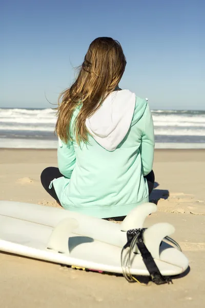Meisje zitten in het strand en de golven controleren — Stockfoto