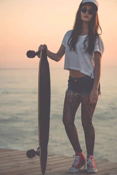 漂亮而时尚的年轻女子拿着滑板摆姿势 — 图库照片