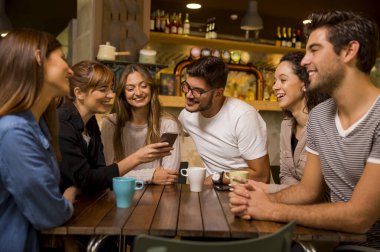 Bir grup arkadaş kafede kahve içip sohbet ediyorlar.