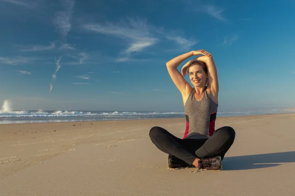 拍一个漂亮的女人在海滩上做伸展运动 — 图库照片
