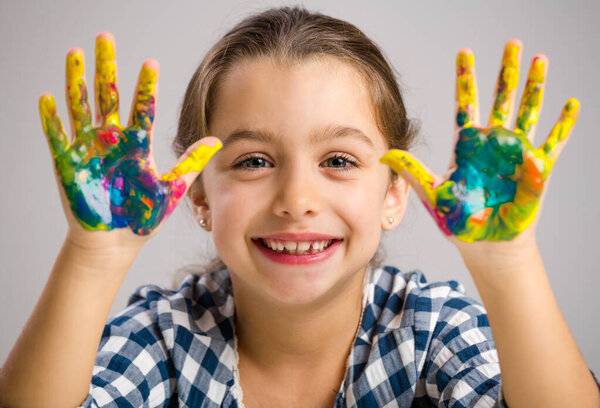 Милая улыбающаяся маленькая девочка с руками в краске
