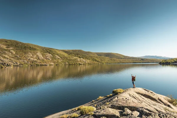 腕を上げて美しい湖の近くをハイキングする男のショット — ストック写真