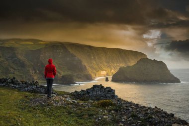 Bir uçurumun tepesinde duran ve manzaranın tadını çıkaran bir kadın, Azores Adası..