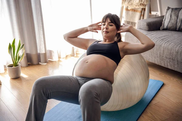 在家里锻炼的怀孕妇女在一个适形球上做运动 在等待婴儿的同时保持良好的体形 — 图库照片