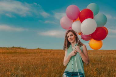 Yeşil çayır üzerinde renkli balonlar ile genç güzel kadın