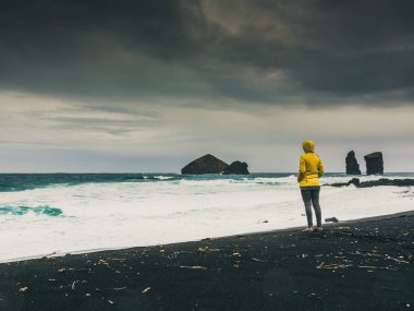 Vahşi bir sahilde tek başına yürüyen bir kadın.