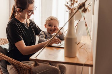 Busy woman working at home with a baby in the la
