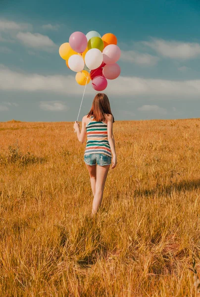 Νεαρή Γυναίκα Στο Πεδίο Κρατώντας Πολύχρωμα Μπαλόνια — Φωτογραφία Αρχείου