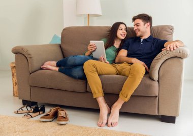 Genç çift kanepede oturan ve bir Tablet bir şey izliyor